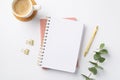 Business concept. Top view photo of workspace open notepad gold pen binder clips eucalyptus sprig and cup of coffee on rattan