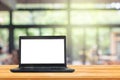 Used black laptop with blank white screen on wooden table and blurry image of coffee shop or cafe restaurant in background. Royalty Free Stock Photo