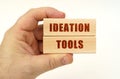 On a white background, a hand that holds wooden blocks with the inscription - Ideation Tools