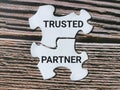 White jigsaw puzzles written trusted partner isolated on wooden background.