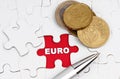 On white puzzles there are coins and a pen, in the open cell there is an inscription - EURO