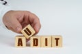 On a white surface, a man stacks cubes with the inscription - AUDIT Royalty Free Stock Photo