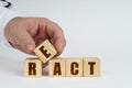 On a white surface, a man stacks cubes with the inscription - REACT