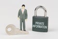 On a white surface there is a figurine of a businessman, a key and a lock with the inscription - Private information Royalty Free Stock Photo