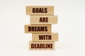 On a white surface are wooden blocks with the inscription - Goals Are Dreams With Deadline