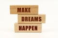 On a white surface are wooden blocks with the inscription - MAKE DREAMS HAPPEN