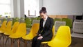 Business concept. A woman sits in the business centre and getting nervous before the interview holding a phone