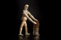 Wooden figure mannequin and stacked coins isolated on black background Royalty Free Stock Photo
