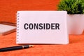 Business concept. Word writing text Consider on a blank notepad page on an orange back