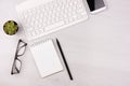 Business concept. Work from home. Office flatlay with white keyboard, reading glasses, pet and notebook. Top view