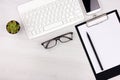 Business concept. Work from home. Office flatlay with white keyboard, reading glasses, pet and notebook. Top view