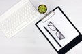 Business concept. Work from home. Office flatlay with white keyboard, reading glasses, pet and notebook. Top view