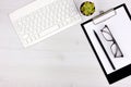 Business concept. Work from home. Office flatlay with white keyboard, reading glasses, pet and notebook. Top view