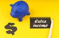 On a yellow background there is a piggy bank, a dollar symbol and paper with the inscription - Extra income Royalty Free Stock Photo