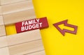 On a yellow surface are wooden blocks and an arrow pointing to a block with the inscription - FAMILY BUDGET Royalty Free Stock Photo