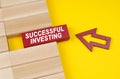 On a yellow surface are wooden blocks and an arrow pointing to a block with the inscription - Successful investing Royalty Free Stock Photo