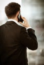 Business concept. Young businessman at the office standing and busy talking on a phone showing with hand he is resolving Royalty Free Stock Photo