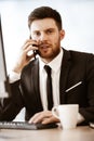 Business concept. Young businessman at the office standing and busy talking on a cell phone resolving a very serious Royalty Free Stock Photo