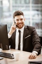 Business concept. Young businessman sitting at the office table happy talking on a cell phone getting good news about Royalty Free Stock Photo