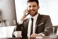 Business concept. Young businessman sitting at the office table happy talking on a cell phone getting good news about Royalty Free Stock Photo