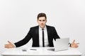 Business Concept: Young businessman working in bright office, sitting at desk, using laptop with serious facial Royalty Free Stock Photo