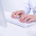 Business concept - Young female doctor woman working at office with computer, typing electronic medical record, white table Royalty Free Stock Photo