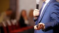 A business conference in the hall. A man talking on the stage using microphone and gives a lecture Royalty Free Stock Photo