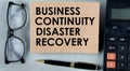 BUSINESS CONTINUITY DISASTER RECOVERY - words on brown paper on the background of a calculator, glasses and a pen Royalty Free Stock Photo