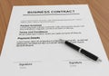 A business contract document is placed on a wooden surface. Royalty Free Stock Photo
