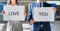 Business couple holding white placard with I love you sign