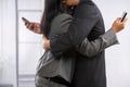 Business couple hug yet still using cell phone