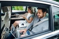 Business couple with laptop sitting on back seats in car, working. Royalty Free Stock Photo