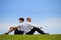 Business couple sitting back to back on grass Royalty Free Stock Photo