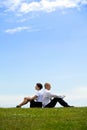 Business couple sitting back to back on grass Royalty Free Stock Photo