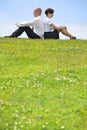 Business couple sitting back to back on grass Royalty Free Stock Photo