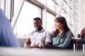 Business Couple Sitting By Window Waiting In Airport Departure Lounge Royalty Free Stock Photo