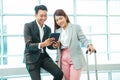 Business couple standing together with baggage and checking flight time. Royalty Free Stock Photo