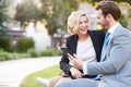 Business Couple Using Digital Tablet On Park Bench Royalty Free Stock Photo