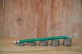 Business Creative and Idea Concept : Used green pencil on stack of silver coins Baht put on wooden table. Royalty Free Stock Photo