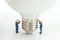 Business creative idea, power or energy generator concept, miniature people figurine engineer worker help building light bulb on