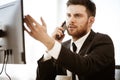 Business crisis concept. Young businessman sitting at the office table busy talking on a cell phone resolving a very Royalty Free Stock Photo