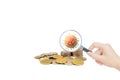 Hand holding magnifying glass and inspecting stacked coins.