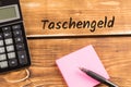 Desk with paper, pen and calculator with german text taschengeld, in english pocket money Royalty Free Stock Photo