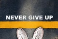 Never give up written on yellow line on asphalt road