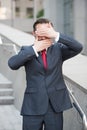 Business director keeping his palms in front of eyes and mouth