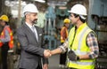 Manufacturing staff engineer in production factory hand shaking with businessman