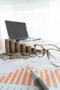 Business documents on table with laptop and coin stacks and graph financial diagram Royalty Free Stock Photo