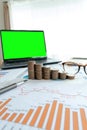 Business documents on table with laptop computer and coin stacks and graph financial diagram. laptop green screen Royalty Free Stock Photo