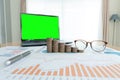 Business documents on table with laptop computer and coin stacks and graph financial diagram. laptop  green screen Royalty Free Stock Photo