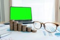 Business documents on table with laptop computer and coin stacks and graph financial diagram. laptop green screen Royalty Free Stock Photo